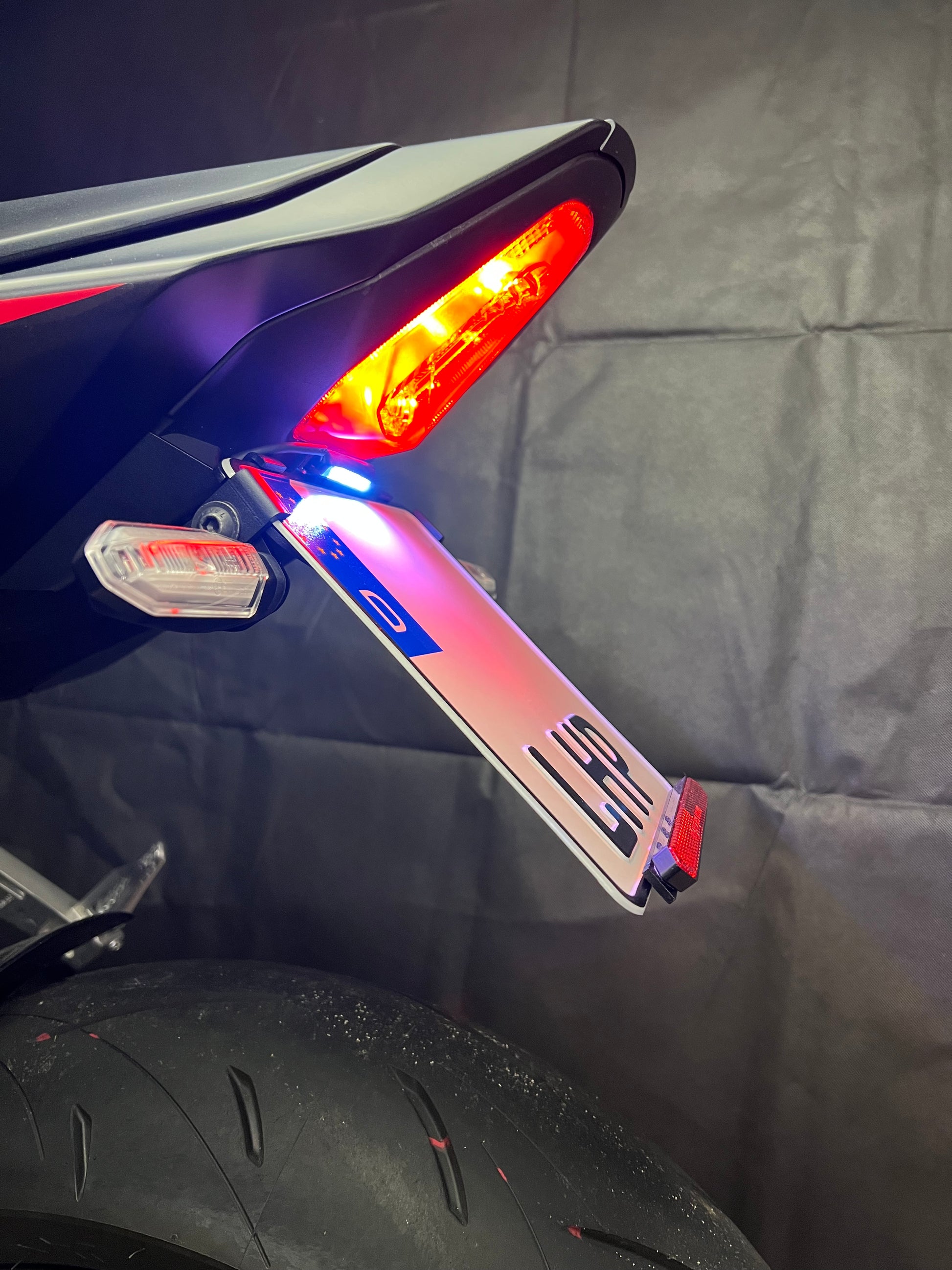 Kurzer, klappbarer Kennzeichenhalter für Honda CB / CBR 650R 2024 aus 3 mm starkem Aluminium, schwarz pulverbeschichtet, mit stufenlos verstellbarem Kennzeichenwinkel und Adapter für originale Blinker.