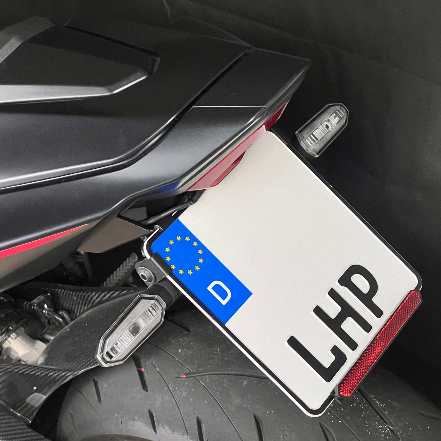 Kurzer, klappbarer Kennzeichenhalter für Honda CB / CBR 650R 2024 aus 3 mm starkem Aluminium, schwarz pulverbeschichtet, mit stufenlos verstellbarem Kennzeichenwinkel und Adapter für originale Blinker.